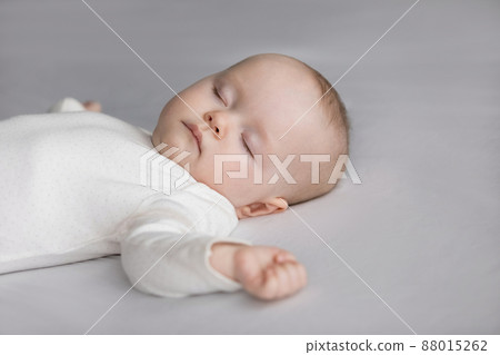 Calm silent adorable baby in white bodysuit sleeping on bed Calm silent adorable baby in white bodysuit sleeping on bed 88015262