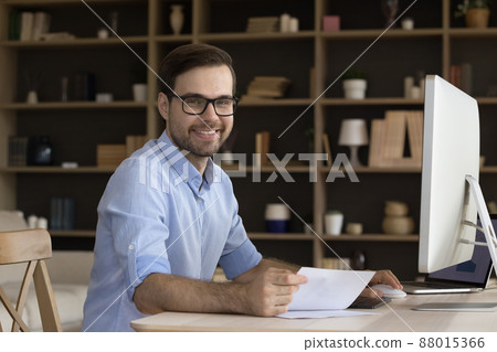 Business portrait smiling young manager sitting by computer at workplace Business portrait smiling young manager sitting by computer at workplace 88015366
