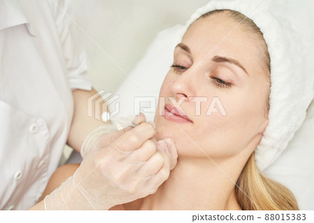 Injection at spa salon. Doctor hands in gloves. Closeup. Pretty female patient 88015383
