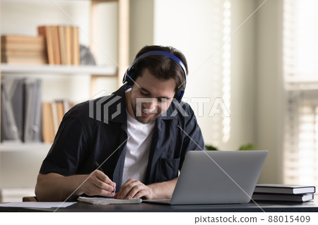 Cheerful student guy in headphones enjoying online studying at laptop 88015409