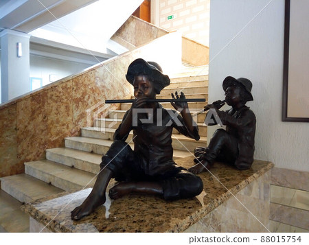 Two bronze statues of boys playing the flute on the landing Two bronze statues of boys playing the flute on the landing 88015754
