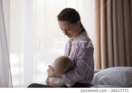 Happy calm young mom enjoying breastfeeding baby, maternity leave 88015755