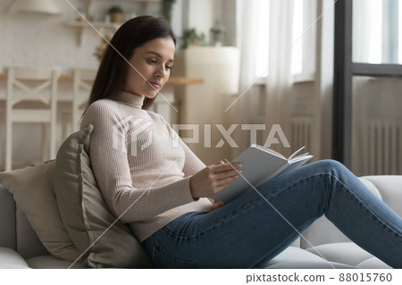 Young woman relax on couch spend leisure reading a book Young woman relax on couch spend leisure reading a book 88015760
