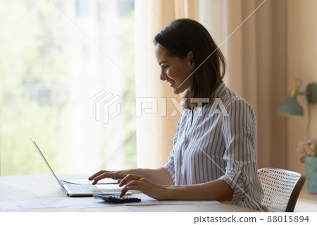 Woman making calculations on calculator, pay bills using laptop 88015894