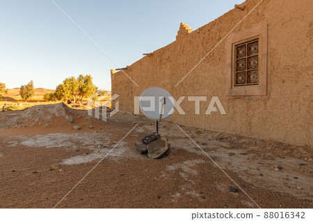 Satellite dish near the house. Berber house in the Sahara desert in Morocco Satellite dish near the house. Berber house in the Sahara desert in Morocco 88016342