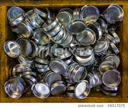 wooden box with batch od stamped shiny metal caps, selective focus top-down wiew wooden box with batch od stamped shiny metal caps, selective focus top-down wiew 88017070