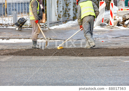 A construction team is patching up the pavement of the carriageway. 88017363