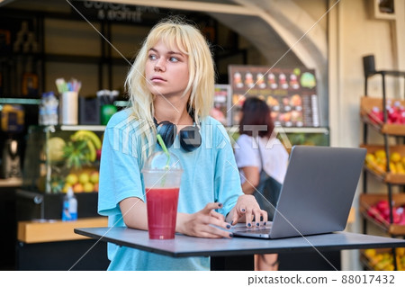 Young woman in outdoor cafe with fruit fresh juice using laptop 88017432