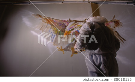 Artist designer draws an eagle on the wall. Craftsman decorator paints picture with acrylic oil color. Painter painter dressed in paint coat. Indoor. Artist designer draws an eagle on the wall. Craftsman decorator paints picture with acrylic oil color. Painter painter dressed in paint coat. Indoor. 88018155