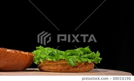 Craft burger is cooking on black background. Consist: sauce, lettuce, tomato, red onion, pickle, cheese, bacon, air bun and marbled meat beef. Craft burger is cooking on black background. Consist: sauce, lettuce, tomato, red onion, pickle, cheese, bacon, air bun and marbled meat beef. 88018198