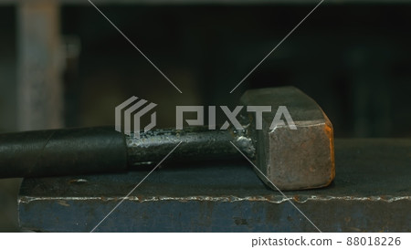Forge workshop. Smithy manual production. Hands of smith with hammer hit on glowing hot metal, on the anvil, the forging process. Forge workshop. Smithy manual production. Hands of smith with hammer hit on glowing hot metal, on the anvil, the forging process. 88018226