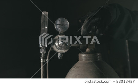 Forge workshop. Smithy manual production. A worker open gas cylinder vessel with oxygen for welding. Cinematic black look. Forge workshop. Smithy manual production. A worker open gas cylinder vessel with oxygen for welding. Cinematic black look. 88018487