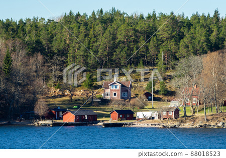 Picturesque summer houses painted in traditional falun red on dwellings island of the Stockholm archipelago in the Baltic Sea in the early morning. Picturesque summer houses painted in traditional falun red on dwellings island of the Stockholm archipelago in the Baltic Sea in the early morning. 88018523