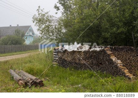 A stack of firewood and logs on the side of the road in the village A stack of firewood and logs on the side of the road in the village 88018889