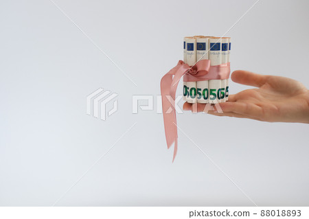 Female hand holding 50 euro bills tied with pink gift ribbon. Money gift. 88018893