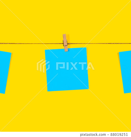 Blue Note papers and decorative pin or clip isolated on yellow background. Office mock up. Top view, flat lay. Colorful office note or sticker papers 88019251