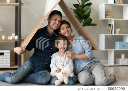 Dreamy happy family sitting on floor under carton roof. 88020090