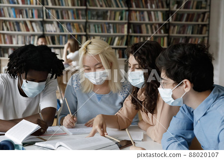 Happy millennial diverse students in facial masks preparing for exams. Happy millennial diverse students in facial masks preparing for exams. 88020107