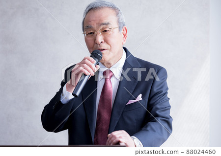 Senior man giving a speech with a business microphone Senior man giving a speech with a business microphone 88024460
