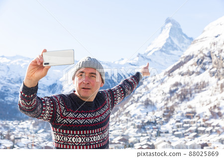 Travel blogger pointing at Matterhorn recording vlog with smartphone 88025869