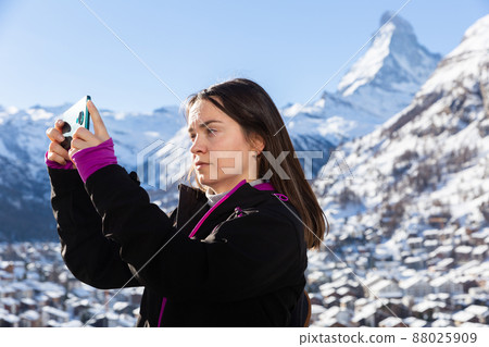 Woman travel blogger using smartphone to record vlog while hiking in Swiss Alps 88025909