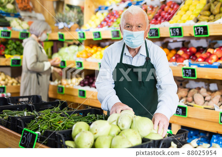 Senior man greengrocer worker setting out goods Senior man greengrocer worker setting out goods 88025954