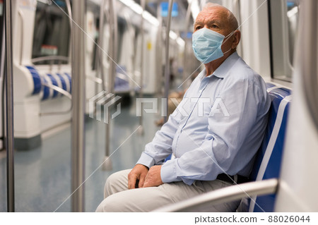 Old man in face mask sitting inside subway train Old man in face mask sitting inside subway train 88026044