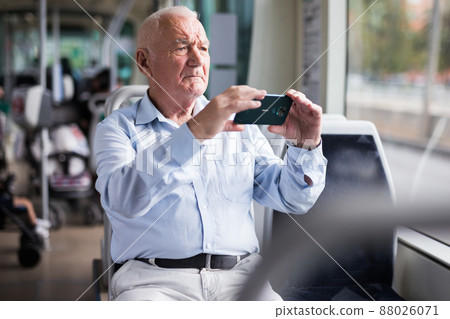 Old man with smartphone in streetcar 88026071