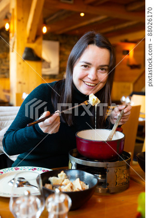 Woman having meal in Swiss restaurant, eating fondue 88026170