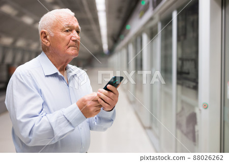 Senior man with smartphone waiting in subway station Senior man with smartphone waiting in subway station 88026262