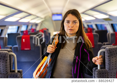 Woman with backpack on shoulder standing in aisle between seats in train 88026427