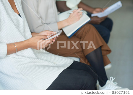 Unrecognizable man and women sitting in queue waiting for job interview using smartphones and making notes 88027361