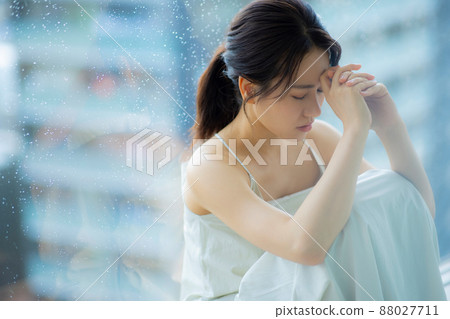 Woman by the window headache worries 88027711