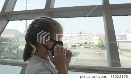 Children caucasian at airport with wearing protective medical mask on head against the background of plane. Coronavirus sars-cov-2 covid-19 2019-ncov. 88028178