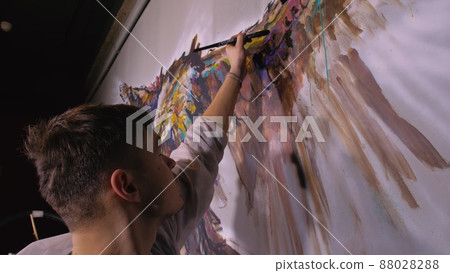 Artist designer draws an eagle on the wall. Craftsman decorator paints picture with acrylic oil color. Painter painter dressed in paint coat. Indoor. Artist designer draws an eagle on the wall. Craftsman decorator paints picture with acrylic oil color. Painter painter dressed in paint coat. Indoor. 88028288