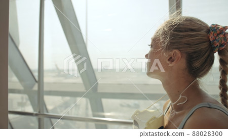 Woman caucasian at airport with wearing protective medical mask on head against the background of the plane. Coronavirus sars-cov-2 covid-19. 88028300