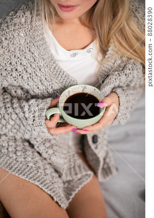 A young woman with a porcelain cup of coffee in her hands. 88028390