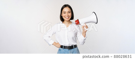 Smiling young asian woman posing with megaphone, concept of news, announcement and information, standing over white background Smiling young asian woman posing with megaphone, concept of news, announcement and information, standing over white background 88028631