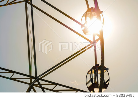Silhouette of ferris wheel rotating against clear sky - sun lens flare Silhouette of ferris wheel rotating against clear sky - sun lens flare 88029495