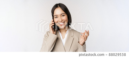 Smiling corporate woman in suit, talking on mobile phone, having a business call on smartphone, standing over white background Smiling corporate woman in suit, talking on mobile phone, having a business call on smartphone, standing over white background 88029538