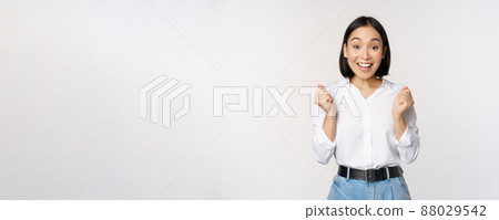 Enthusiastic asian woman rejoicing, say yes, looking happy and celebrating victory, champion dance, fist pump gesture, standing over white background Enthusiastic asian woman rejoicing, say yes, looking happy and celebrating victory, champion dance, fist pump gesture, standing over white background 88029542