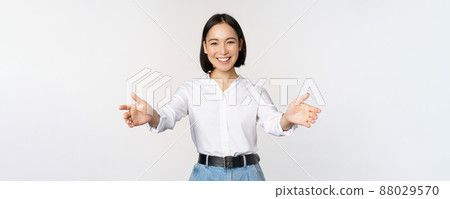 Image of smiling asian woman welcoming guests clients, businesswoman stretching out open hands, greeting, standing over white background 88029570