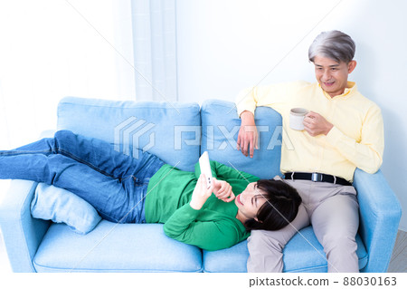 Parent and child of middle father and young daughter relaxing on the sofa in the living room 88030163