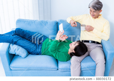 Parent and child of middle father and young daughter relaxing on the sofa in the living room Parent and child of middle father and young daughter relaxing on the sofa in the living room 88030172