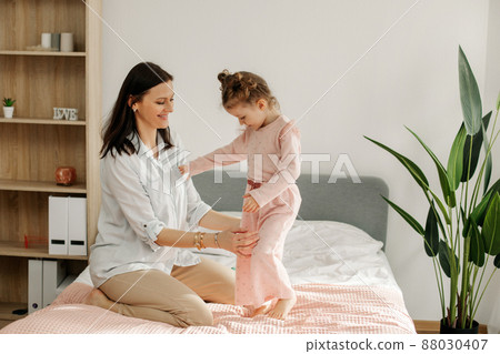 A young mother plays with her baby in the bedroom. Happy loving family. A young mother plays with her baby in the bedroom. Happy loving family. 88030407