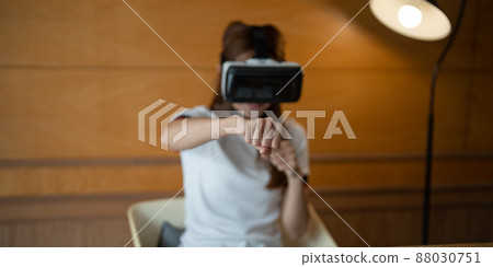 Girl wearing virtual reality glasses on head playing fighting game, holding clenched fists up ready to boxing, experiencing cyberspace using VR headset technology 88030751