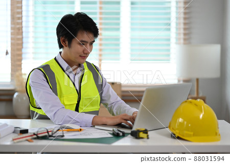 Young Asian Engineer working on construction plan and using laptop computer at office. 88031594
