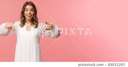 Portrait of enthusiastic upbeat young blond woman pointing fingers down to invite you check-out product, showing bottom advertisement, smiling camera cheerful, spring concept, pink background Portrait of enthusiastic upbeat young blond woman pointing fingers down to invite you check-out product, showing bottom advertisement, smiling camera cheerful, spring concept, pink background 88032265