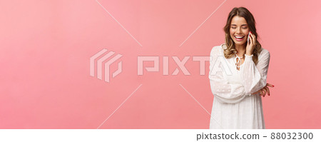 Communication and technology concept. Attractive caucasian female in white dress, blond short haircut, hold smartphone, talking on mobile phone and laughing, smiling carefree, pink background Communication and technology concept. Attractive caucasian female in white dress, blond short haircut, hold smartphone, talking on mobile phone and laughing, smiling carefree, pink background 88032300