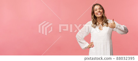 Enthusiastic lovely young woman in white cute dress, show thumb-up in approval, recommend product, smiling satisfied, leave positive review, impression, standing pink background 88032395